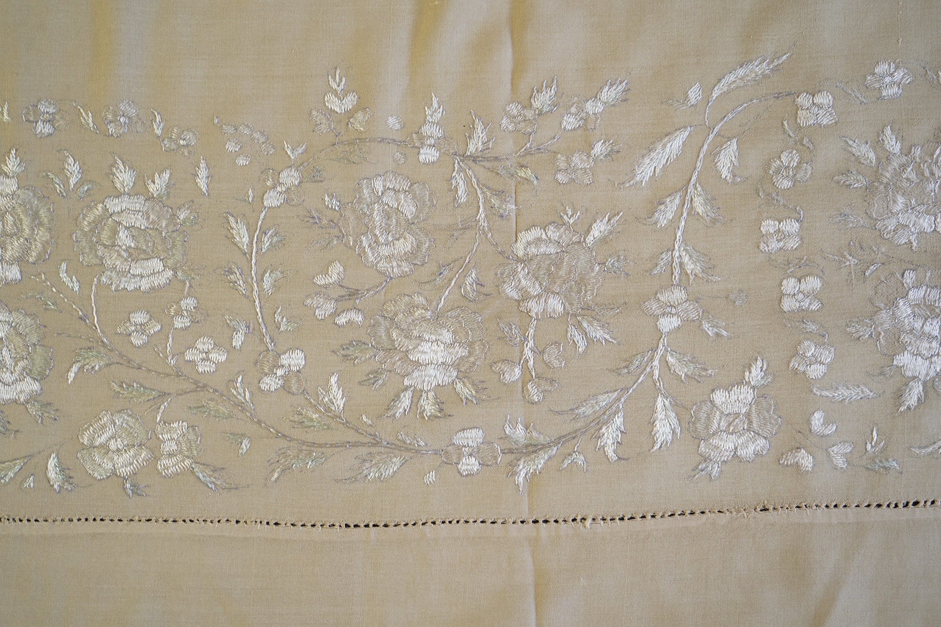 A 1920’s heavy shantung silk hand embroidered table cover. Worked with decorative rows of button hole stitch. Embroidered with white, green and blue silk flowers. 240cm x 204cm. Condition - some fine holes near corners,
